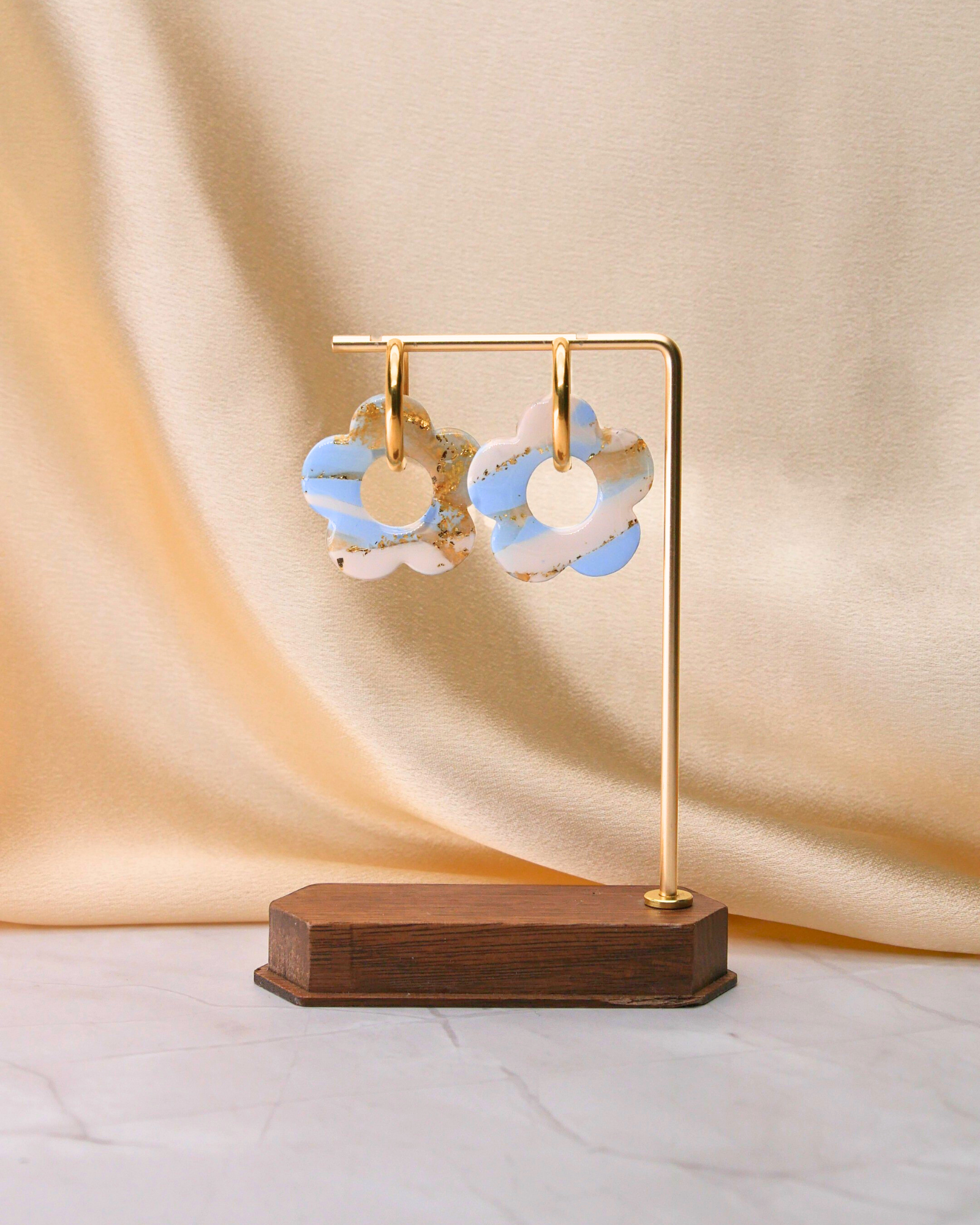 Créoles dorées avec grandes fleurs bleu clair et blanc, fabriquées à la main en argile polymère et résine, design unique Maison Oneiri