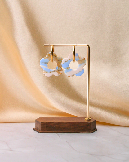 Créoles dorées avec grandes fleurs bleu clair et blanc, fabriquées à la main en argile polymère et résine, design unique Maison Oneiri